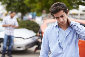 man scratching his neck, car in accident in the back